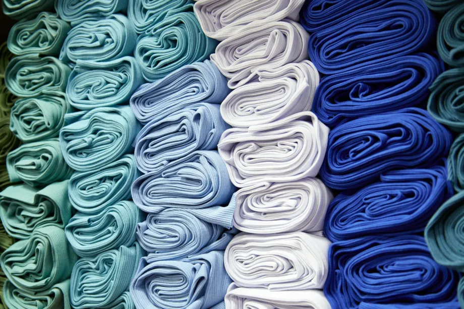 Rolled fabrics stacked in columns of teal, pale blue, white and royal blue