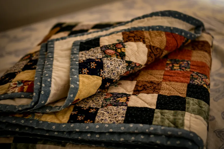 Folded scrappy patchwork quilt of small print squares with a blue dotted binding