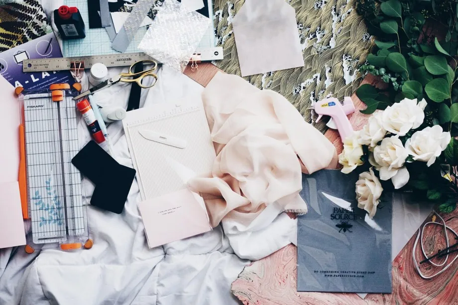 A quilter in a home studio cuts fabric on a cutting mat while following a printed quilt pattern.